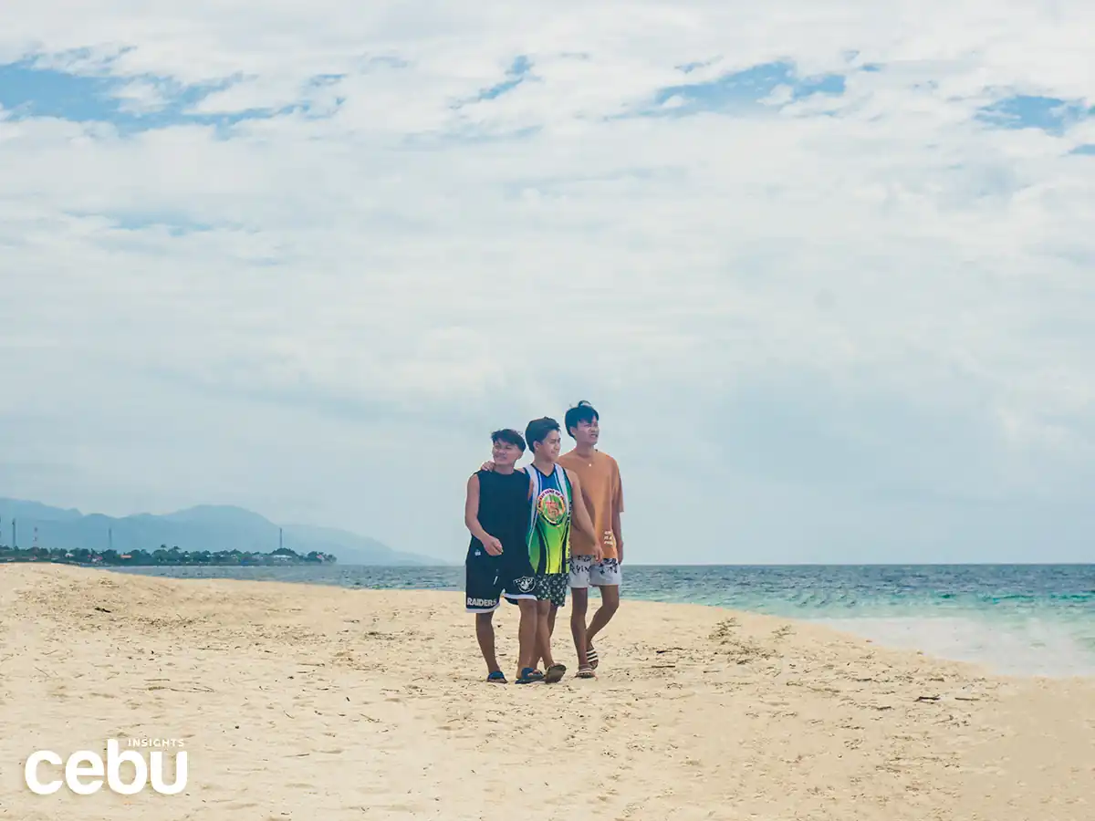 Three boys walking along the shore of the Basdaku White Beach
