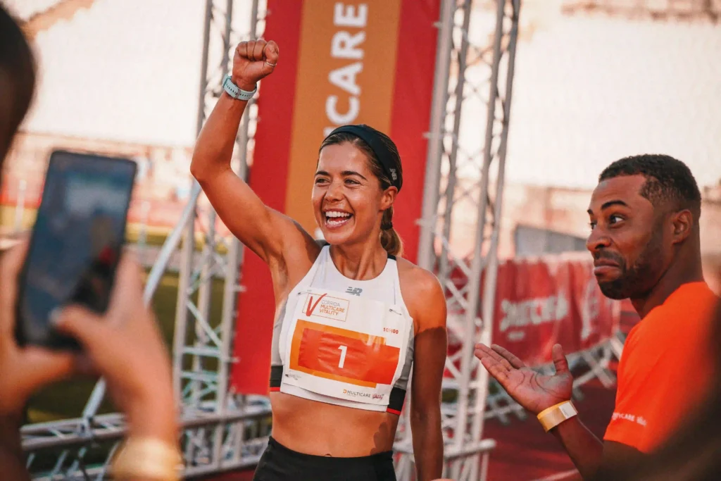A photo of a woman smiling in a white running top