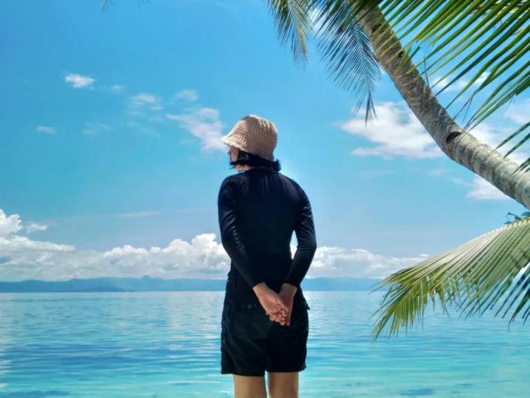 A woman who is solo traveling, standing at the beach and facing the sea