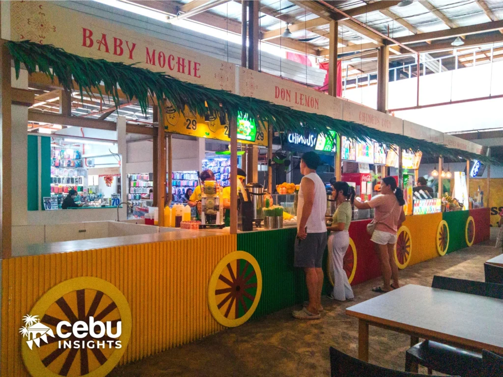 Customers buying lemonade at colorful kiosks at Pusô Village