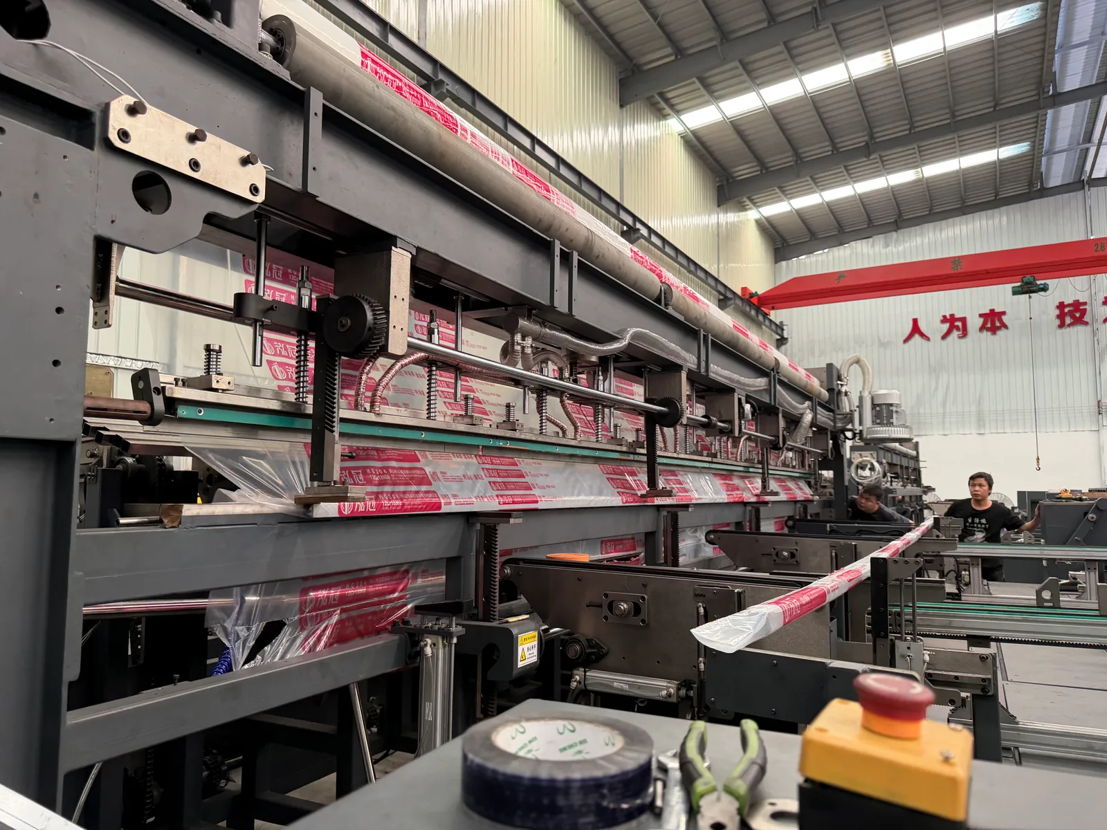 Side view along a packaging machine with printed film and a worker at the far end