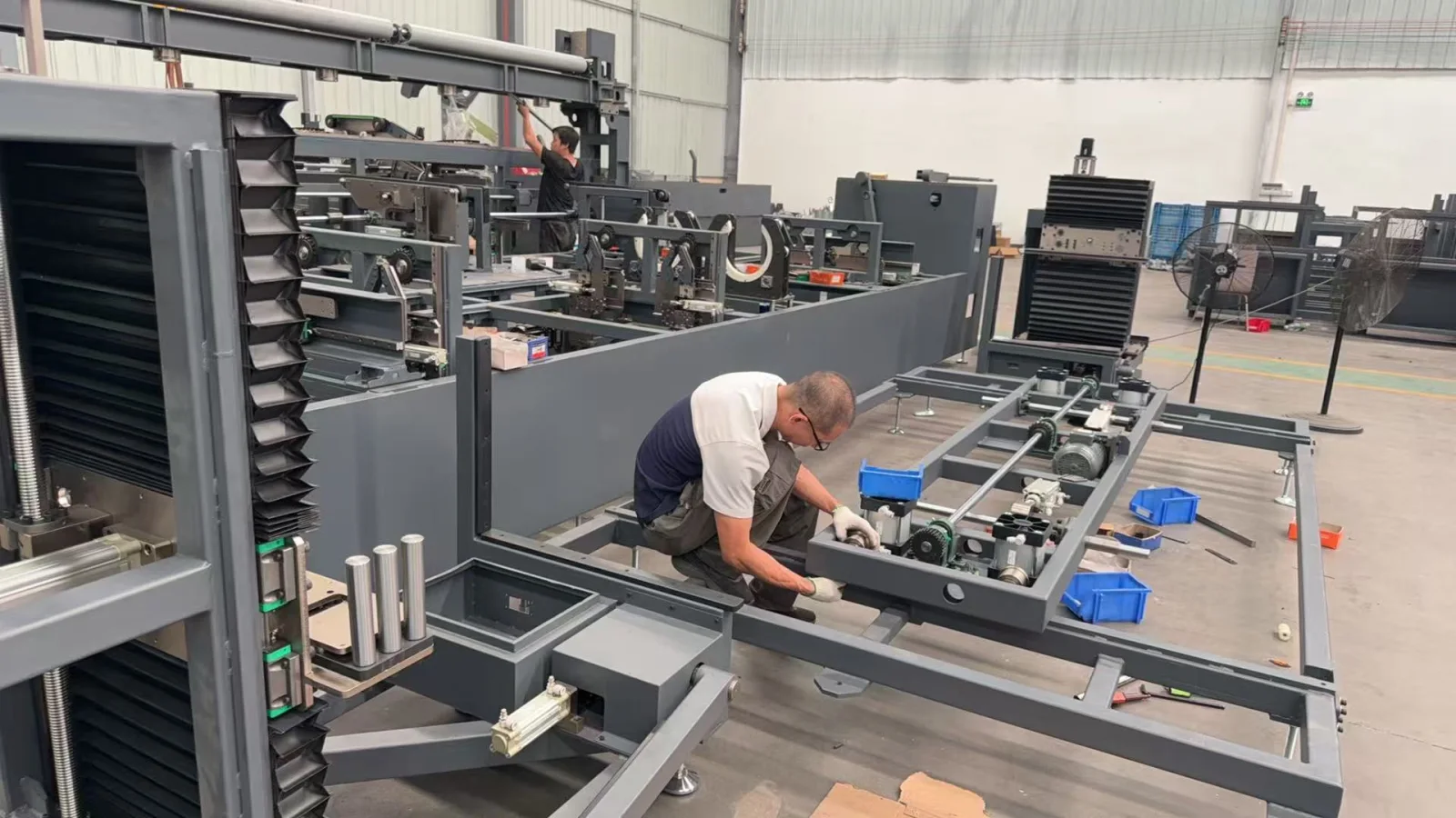 People working on an exposed machine frame and its conveyor components