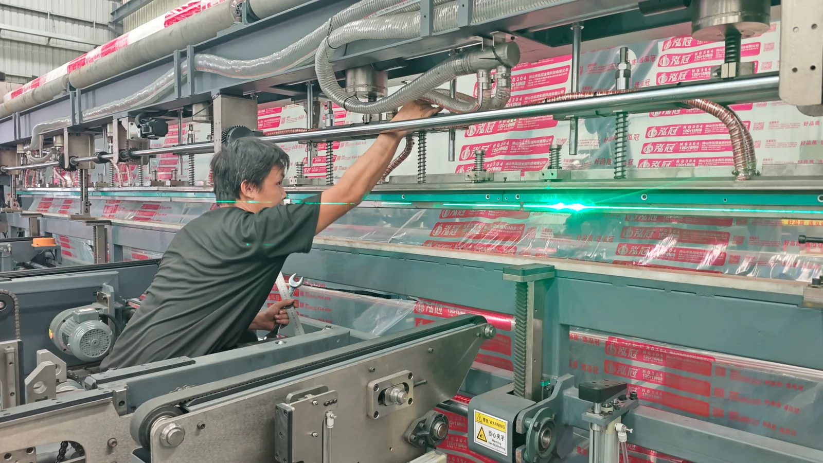 A worker handling printed film on packaging equipment in the workshop