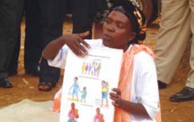 A woman in Burundi teaches optimal practices for children's health using a poster, part of the Tubaramure (let's help them grow) program. Behavior change communication is a critical pathway for improving health and nutrition practices. Photo by Megan Parker