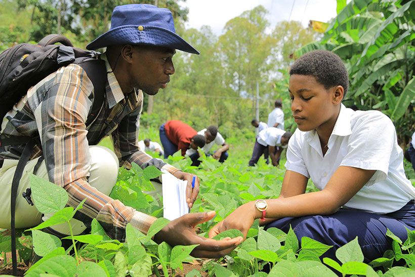 The founder of NEWDAY Afrika, Prince Bobo Tangabanga, talking to a secondary school student on the school farm.