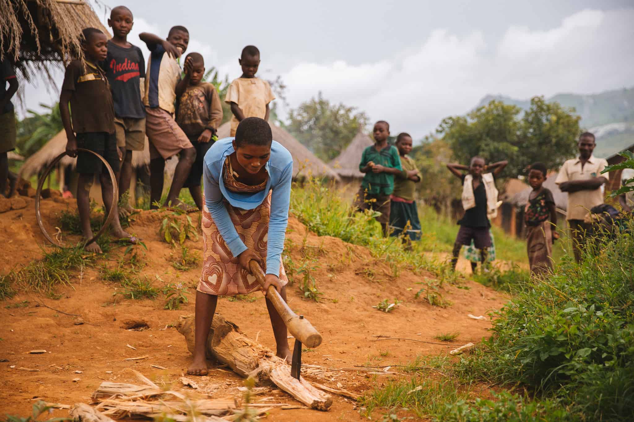 Young Women Chopping Wood as Group of Boys Watch, Malawi