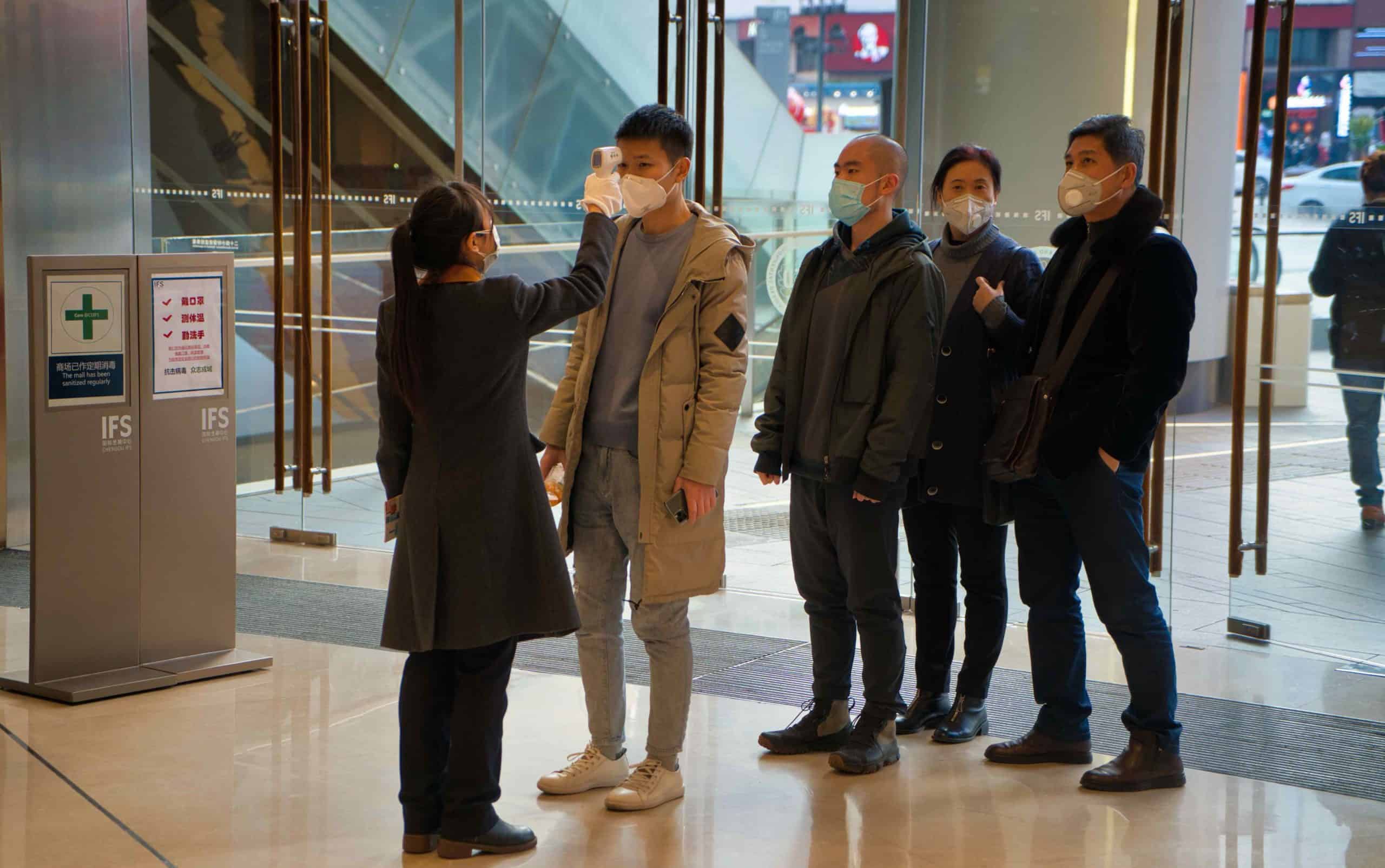 People undergo temperature screenings at a building in Chengdu, China. Restrictions to control COVID-19 have slowed economies but not yet seriously disrupted food security.