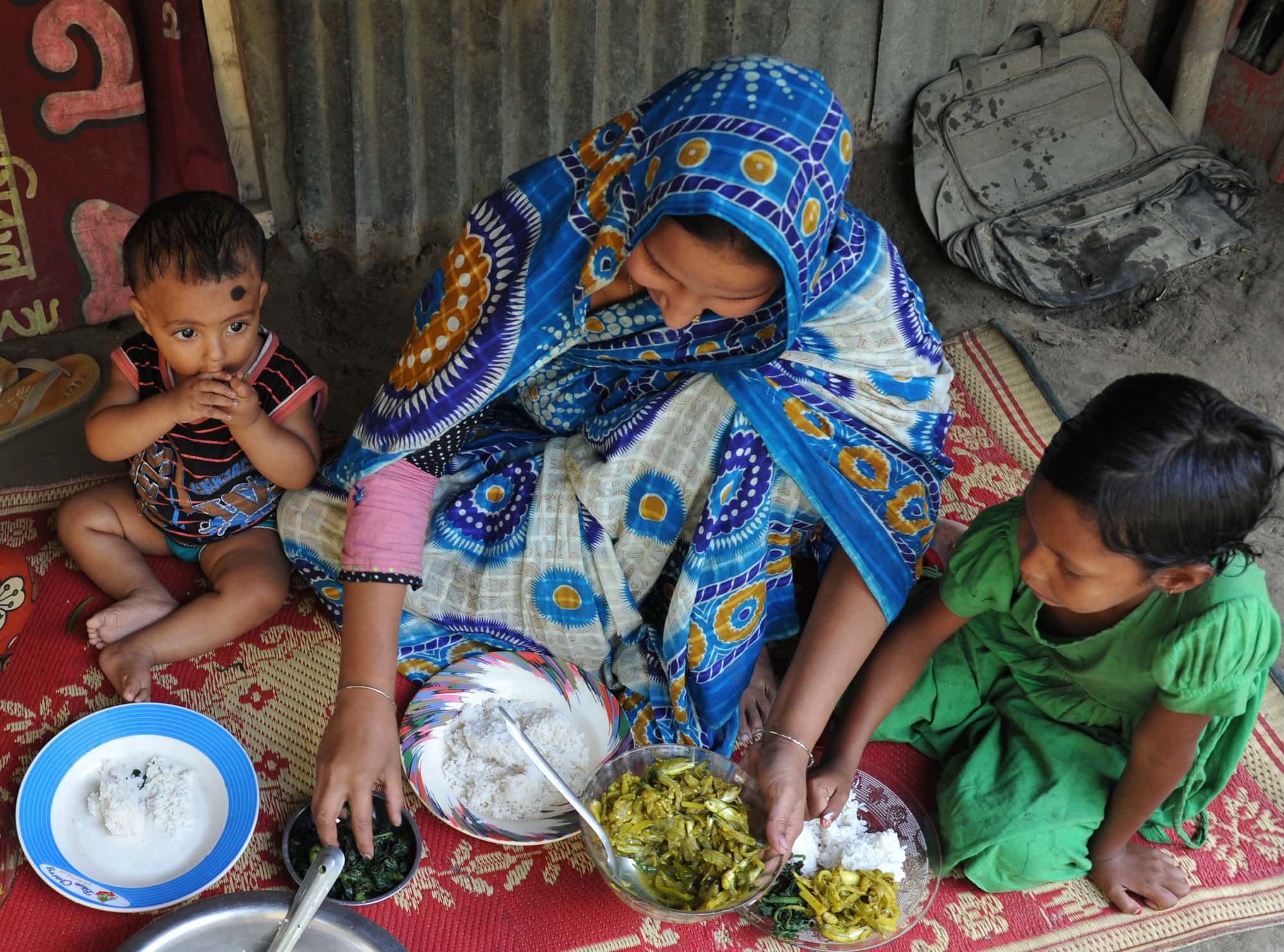 A Bangladeshi mother feeding her children nutrient-rich small fish and leafy vegetables. Photo by Finn Thilsted.