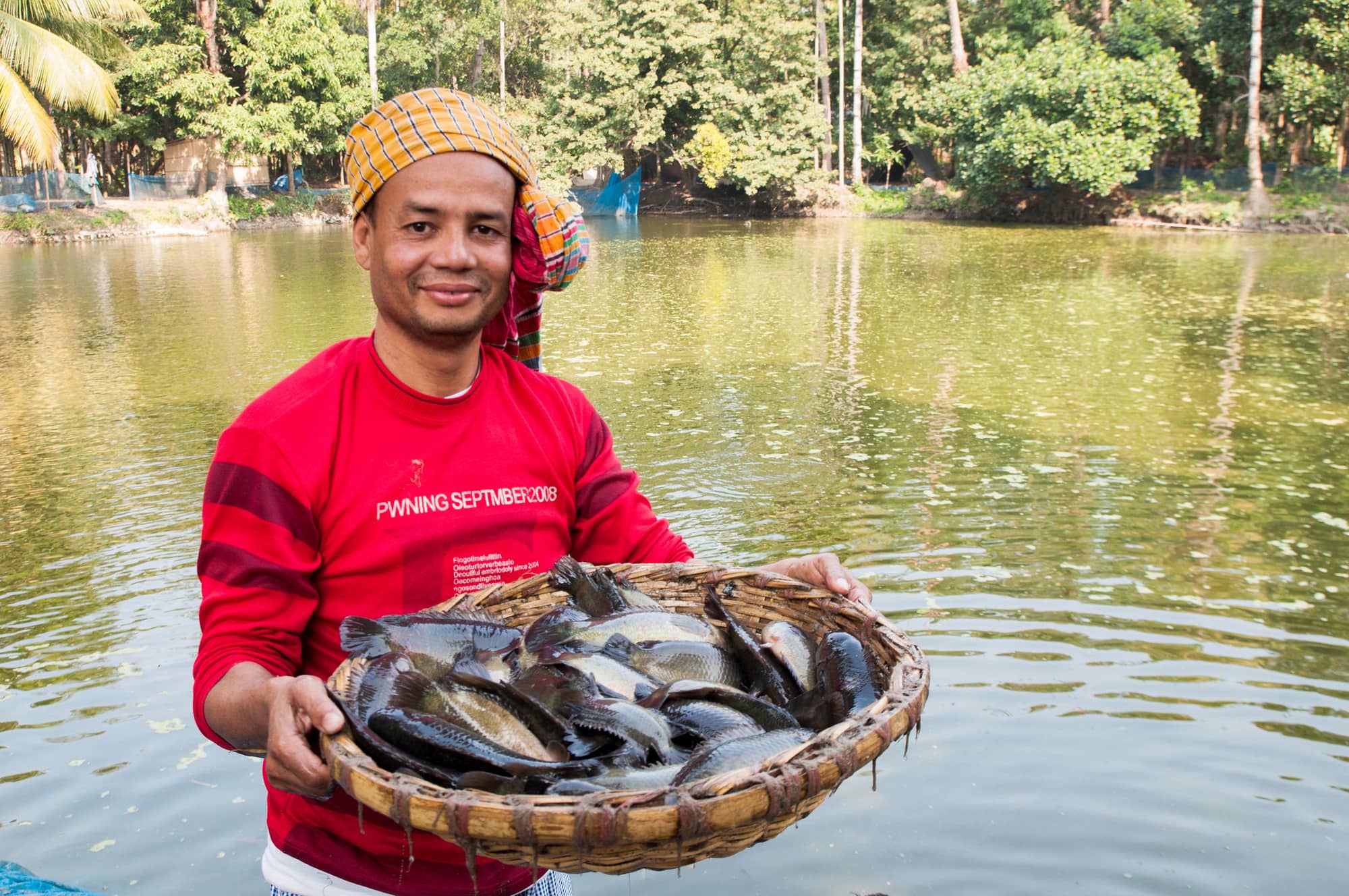 A Bangladeshi farmer poses with the climbing perch fish harvested from his aquaculture pond. The Gates Foundation is in the process of investing in the country’s smallholder aquaculture sector. Photo by Balaram Mahalder.