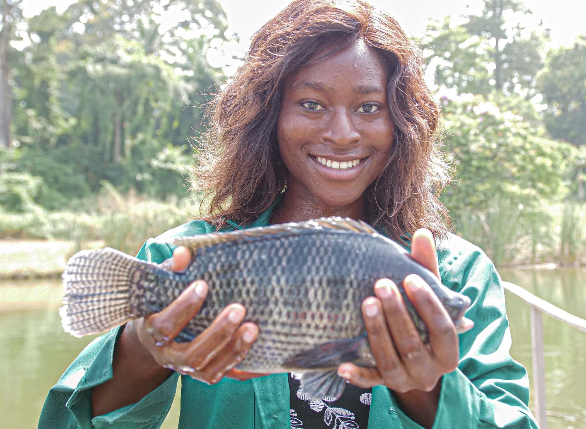 Nigerian youth entrepreneur poses with her farmed tilapia
