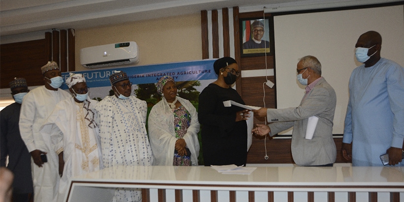 (L-R) Commissioner for Reconstruction, Rehab, Reintegration and Humanitarian Service, Adamawa State, Mr Elijah Tumba; Commissioner for Livestock and Aquaculture Development, Mr Usman Yahaya Diyajo; District Head of Yola, Alhaji Mohammed Mustapha; Commissioner for Agriculture, Hon. Umar Iya Daware; Commissioner for Women Affairs and Social Development, Mrs Lami Ahmed; Chief Executive Officer, Fadhila Crop Science Ltd., Ms Nanona Usoro; Chief of Party, Nigeria Integrated Agriculture Activity (NIAA), Dr Prakash Kant Silwal; and Deputy Chief of Party (NIAA), Mr Olukayode Faleti after exchanging the signed MoU.