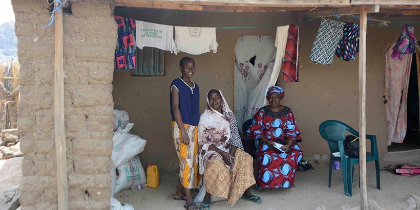 Rebecca Ezekiel (center) with her undergraduate daughter, Peace, and Extension Agent Juliana Naphtali, in front of her new house.