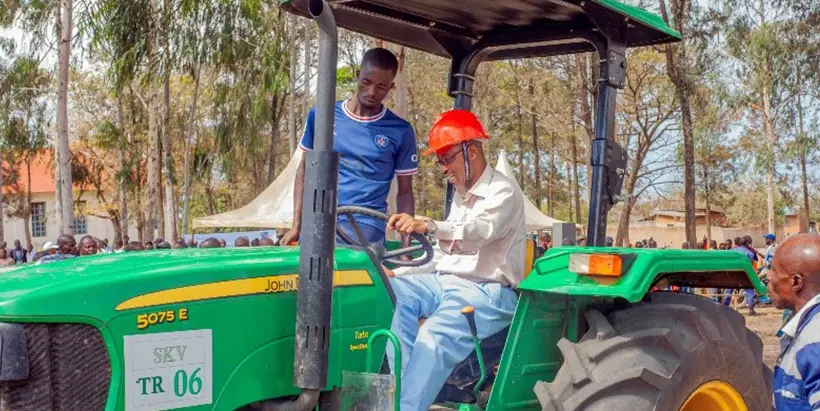 Uvira Territory Administrator Bonheur Kayamba being shown how to use a tractor.