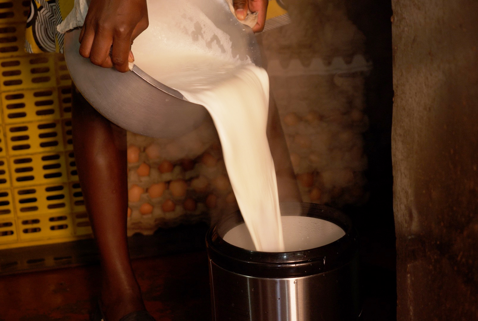 Person pouring boiled milk from a saucepan into a container