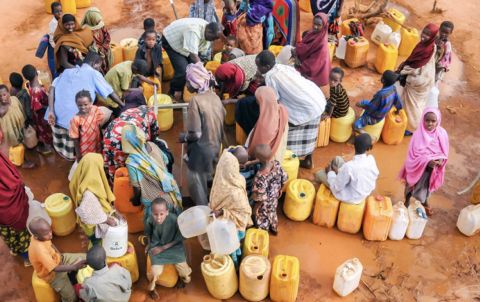 Migrants at a refugee camp in Dadaab, Somalia, gather around spigots to collect water