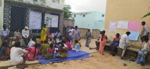 Photo showing a group discussion around a board in a village setting