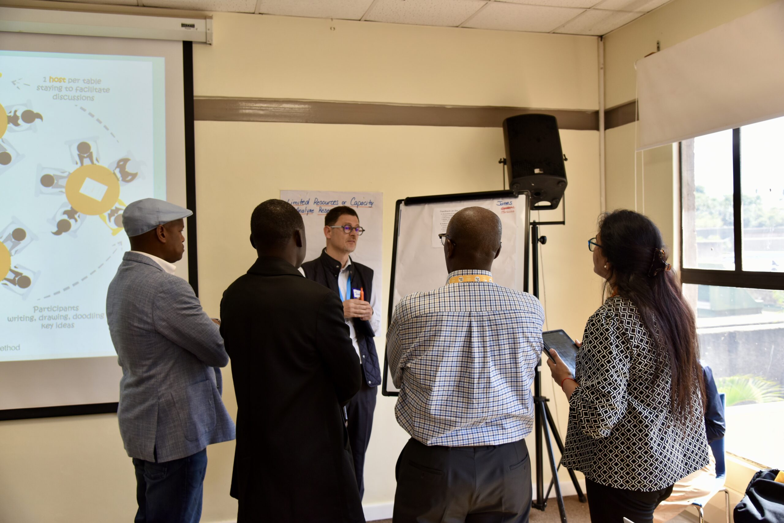 A group of people stand around a flipchart