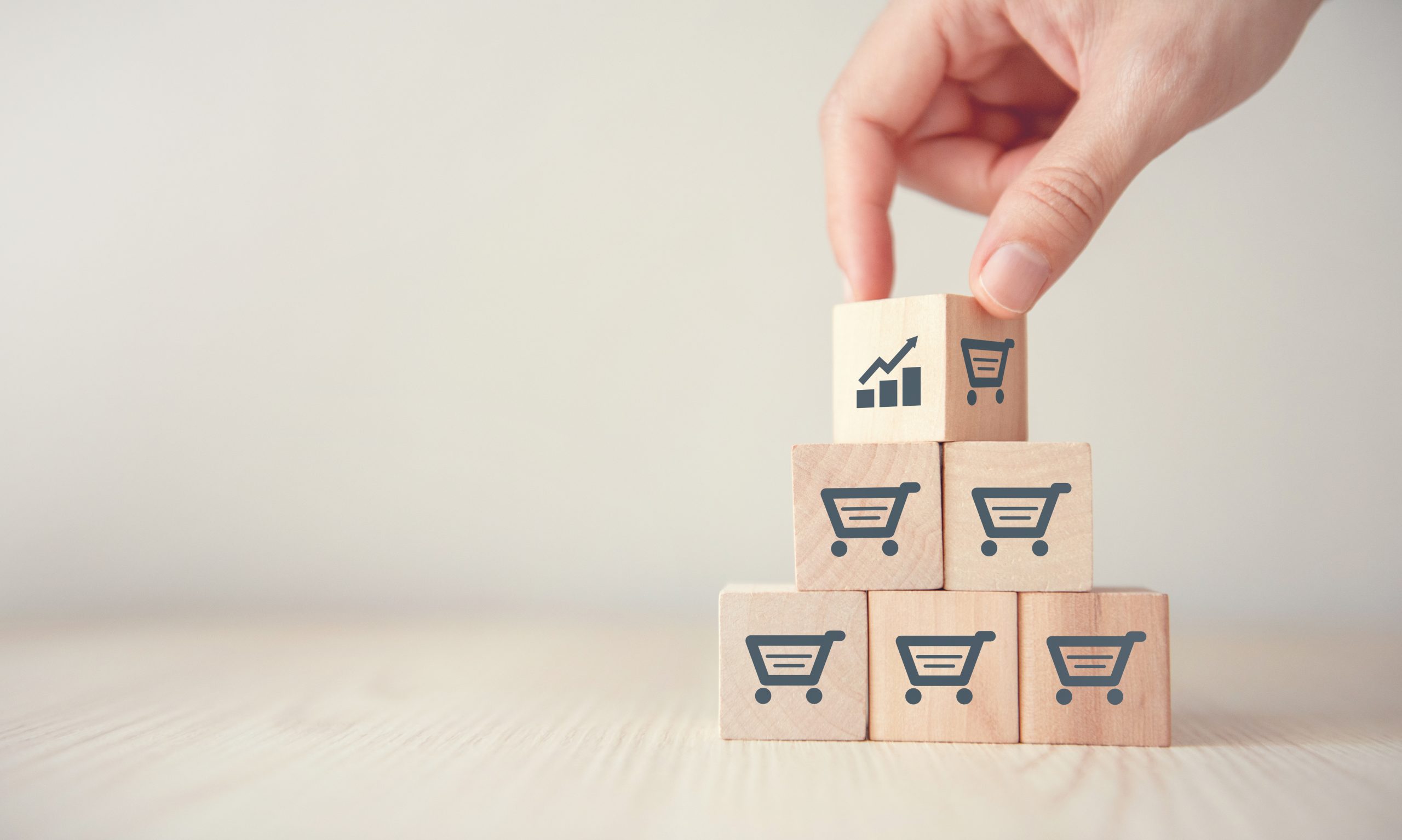 Wooden blocks with ecommerce shopping carts on them, representing the pillars of a good ecommerce strategy.