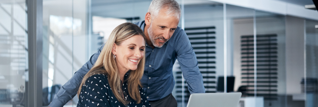 two people smiling looking at a laptop