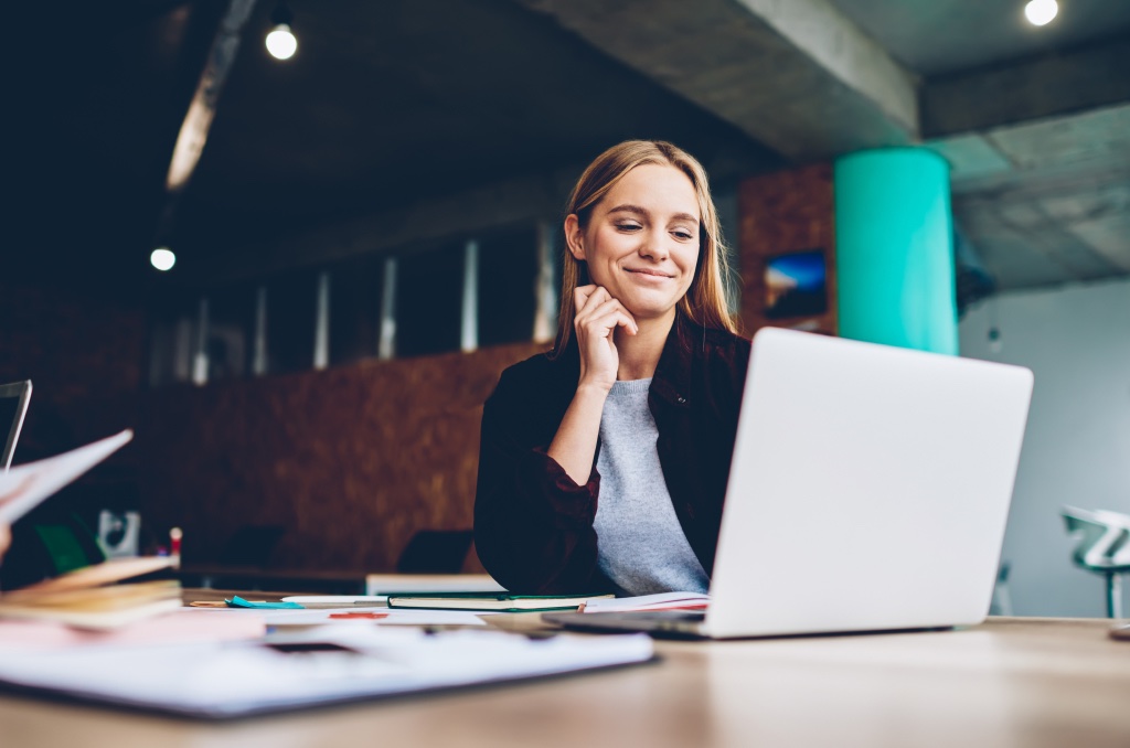 Smiling woman in office setting with laptop