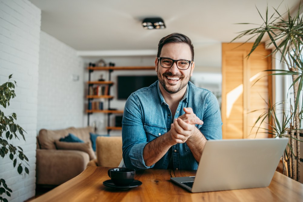 Smiling man on laptop talking to visitors via Chat Software