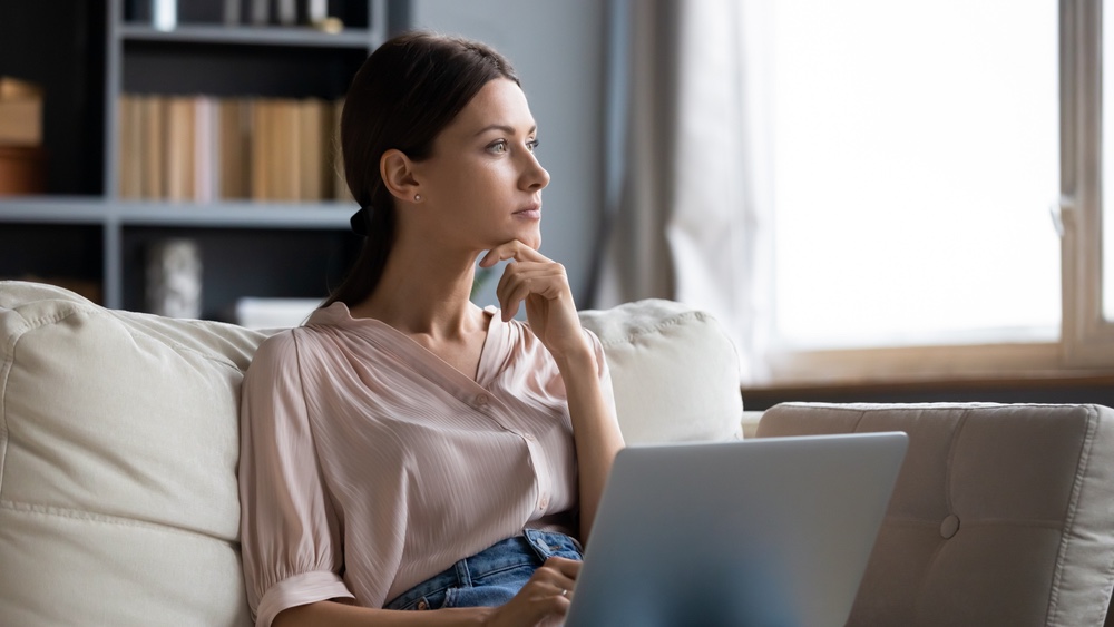 Woman thinking while browsing website on laptop