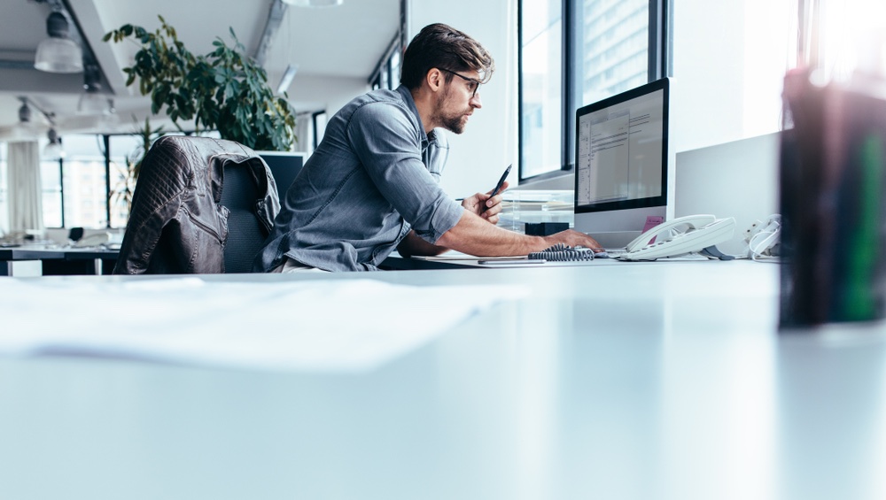 Man sat at desktop computer typing on live chat widget