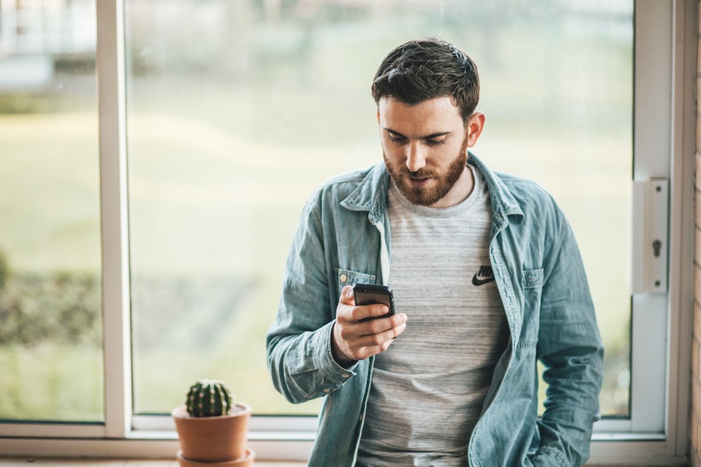 Man at home on smartphone talking t chat agent