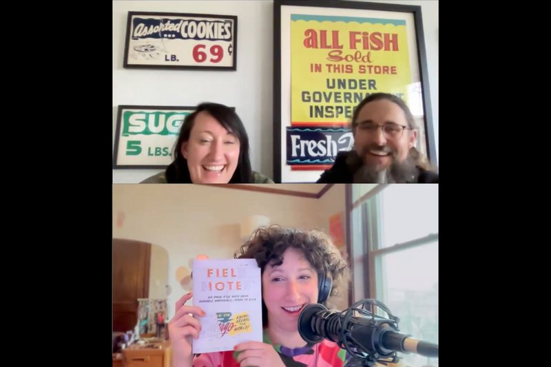 A screenshot from a Zoom call. The top speakers are a woman with long brown hair and a man with a long beard and glasses in front of framed vintage signs for cookies, fish, and sugar. The bottom speaker is a woman with brown curly hair, wearing headphones and speaking into a microphone. She holds up a notebook by Field Notes featuring a design from Heart and Bone Signs.