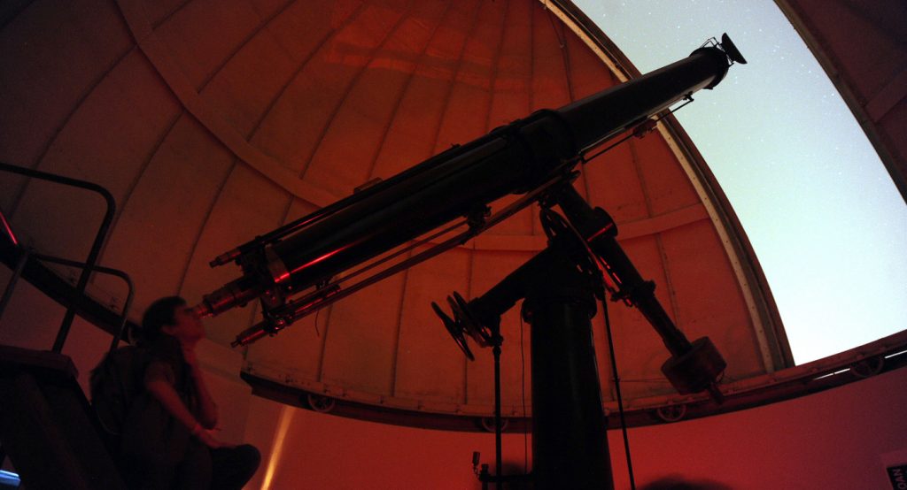 Imagen de una mujer mirando por uno de los telescopios del observatorio Cerro Calán