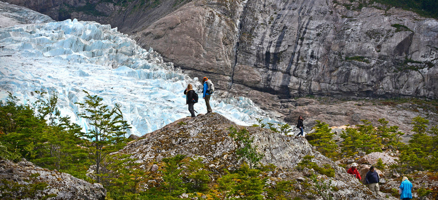 Vista panorámica del Glaciar Serrano, donde se aprecia a dos turistas admirando las bellezas del lugar