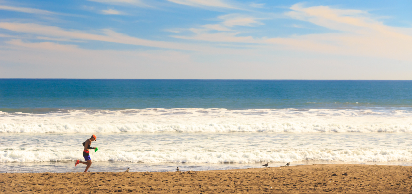 Imagen panorámica de la playa de La Serena en un día soleado donde se ve el cielo muy azul y las olas del mar rompiendo en la orilla. 