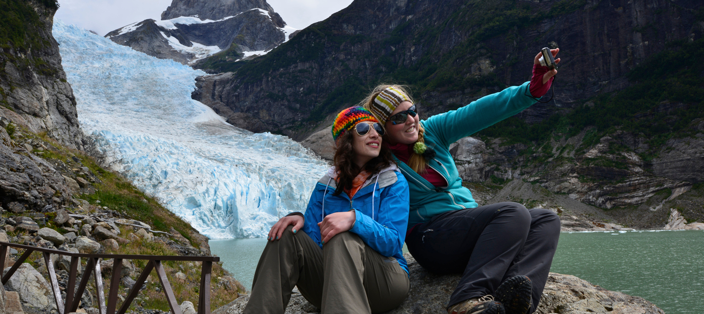 Imagen de dos turistas tomándose selfies con el Glaciar Serrano en sus espaldas en el Parque Nacional Bernardo 0'Higgins