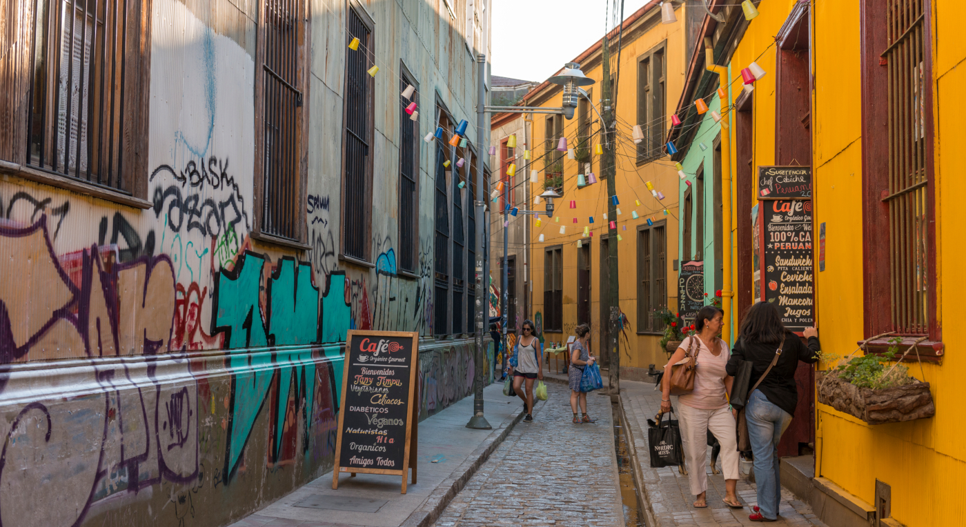 Imagen de los pasajes de Valparaíso, sus coloridas casas y turistas recorriendo sus atractivos.