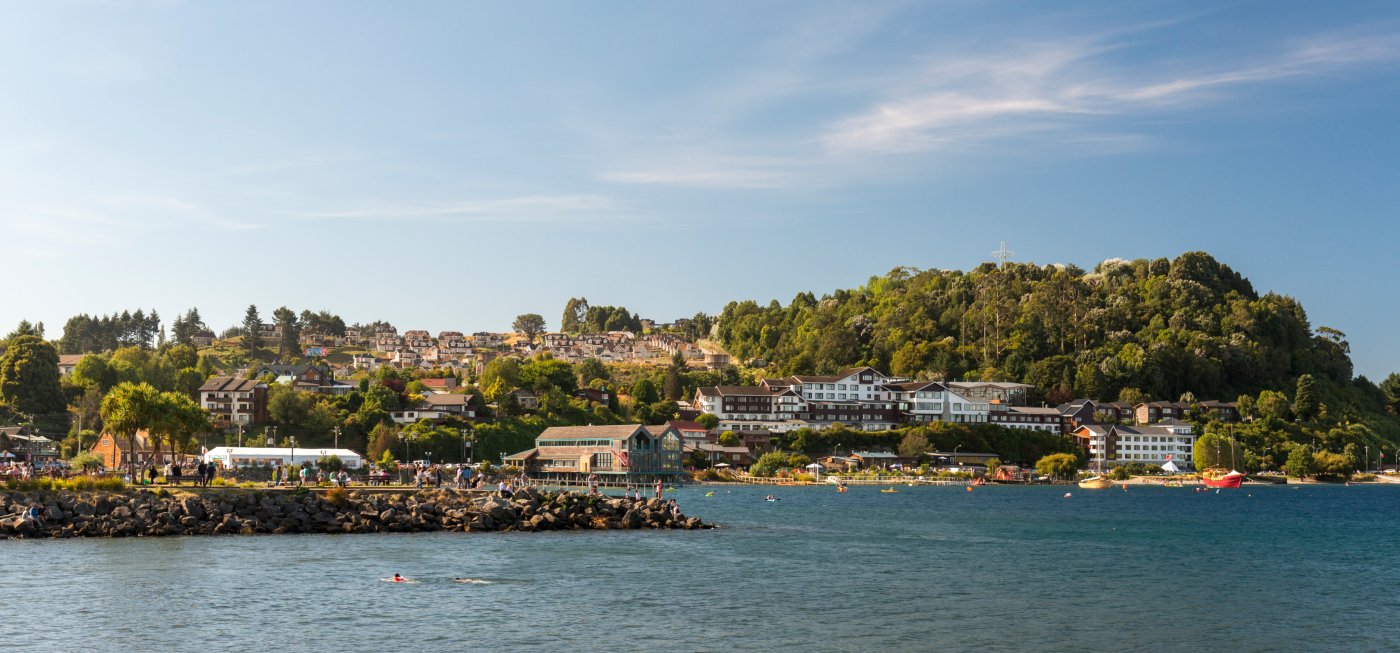 Imagen de la bahía de Puerto Varas, donde se lucen las casas, la vegetación de fondo y las tranquilas aguas del lago Llanquihue