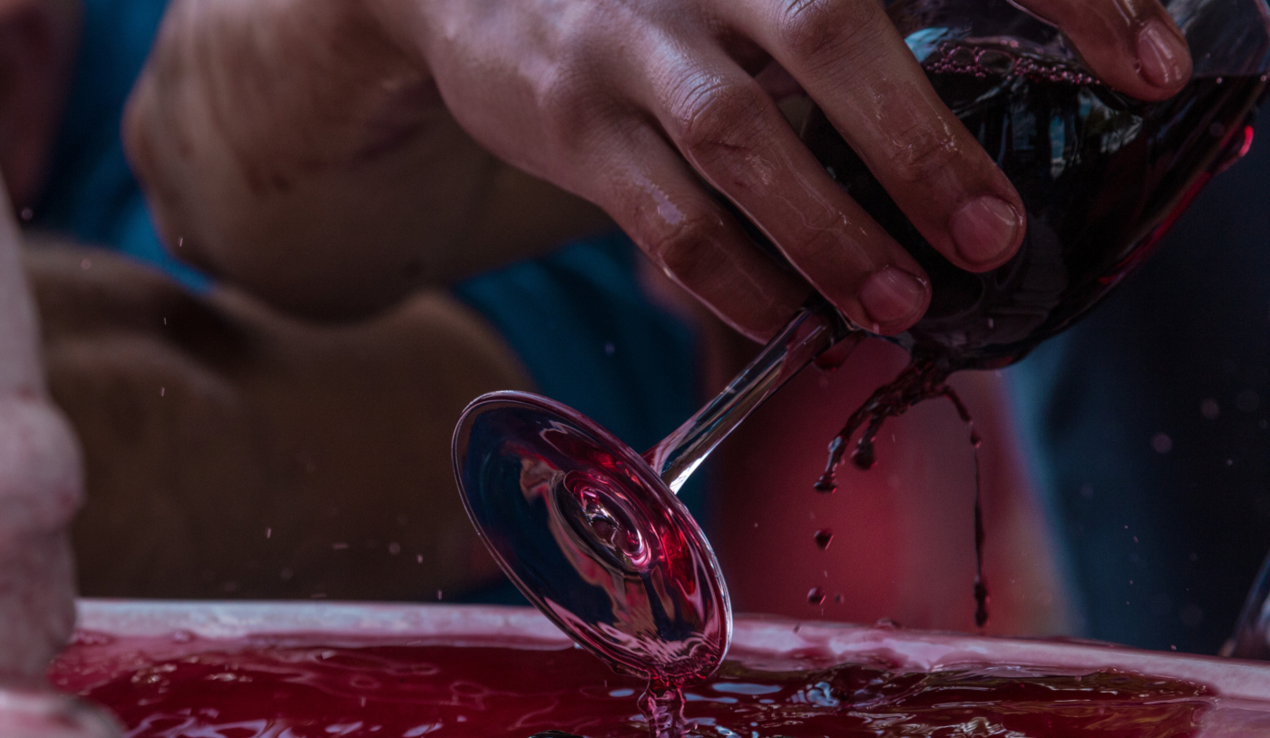 Imagen de la mano de una persona sosteniendo una copa llena de vino tinto