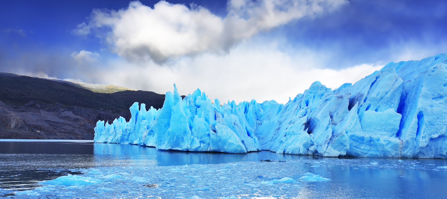 Imagen impactante del glaciar Grey en la Patagonia chilena, donde se ve el azul de los hielos eternos en contraste con las nubes blancas y el cielo despejado.