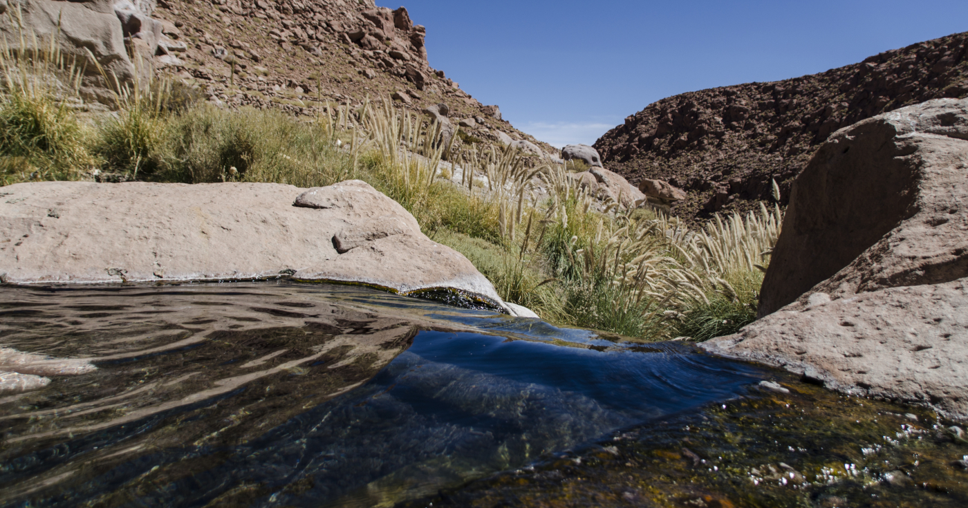 Imagen de las aguas prístinas de las Termas de Puritama, piscina natura en medio de un ambiente rocoso y rodeado de montañas 