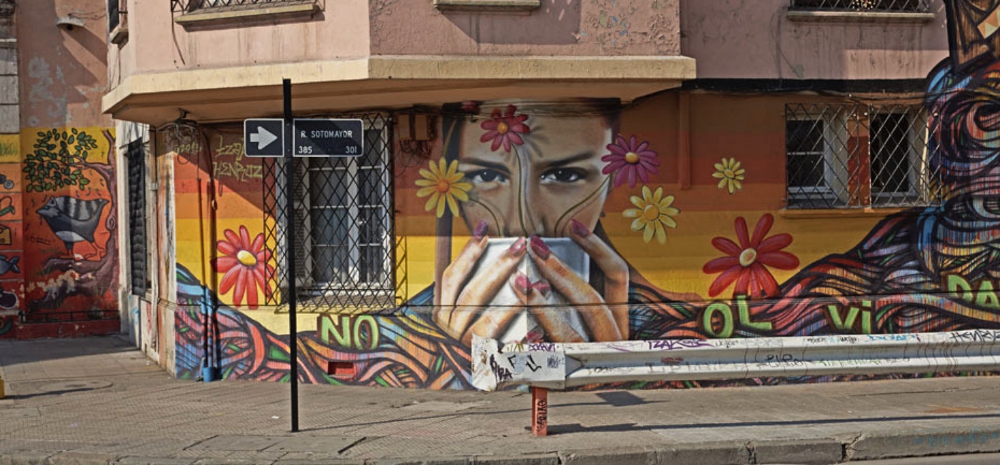 Imagen de un graffiti de la ciudad de Santiago donde se ve una mujer tomando cafe en coloridas tonalidades