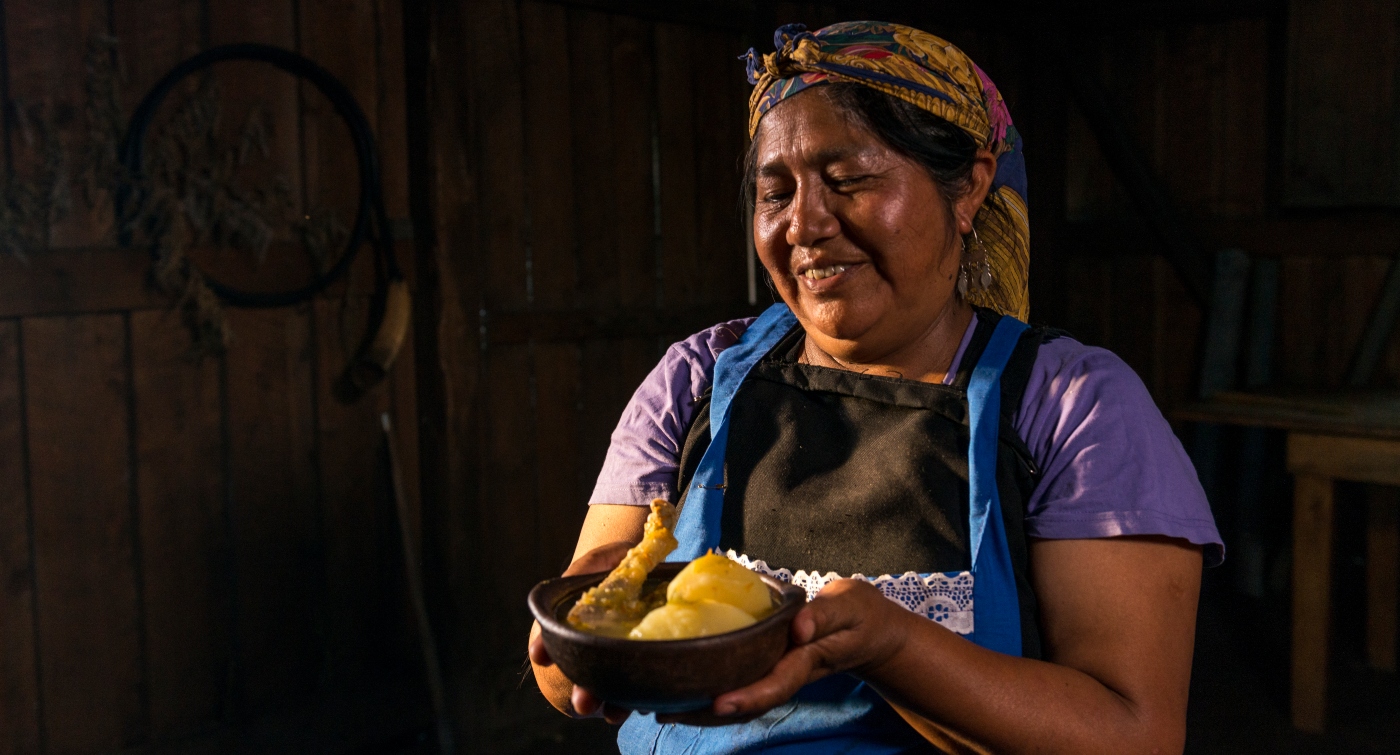 Imagen de una mujer mapuche con una cazuela tradicional en sus manos