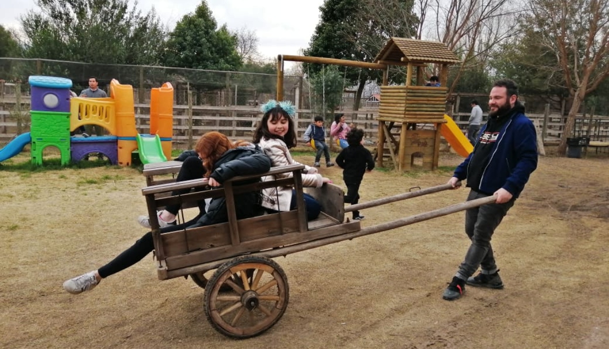 Imagen de un padre jugando con sus dos hijas en una granja