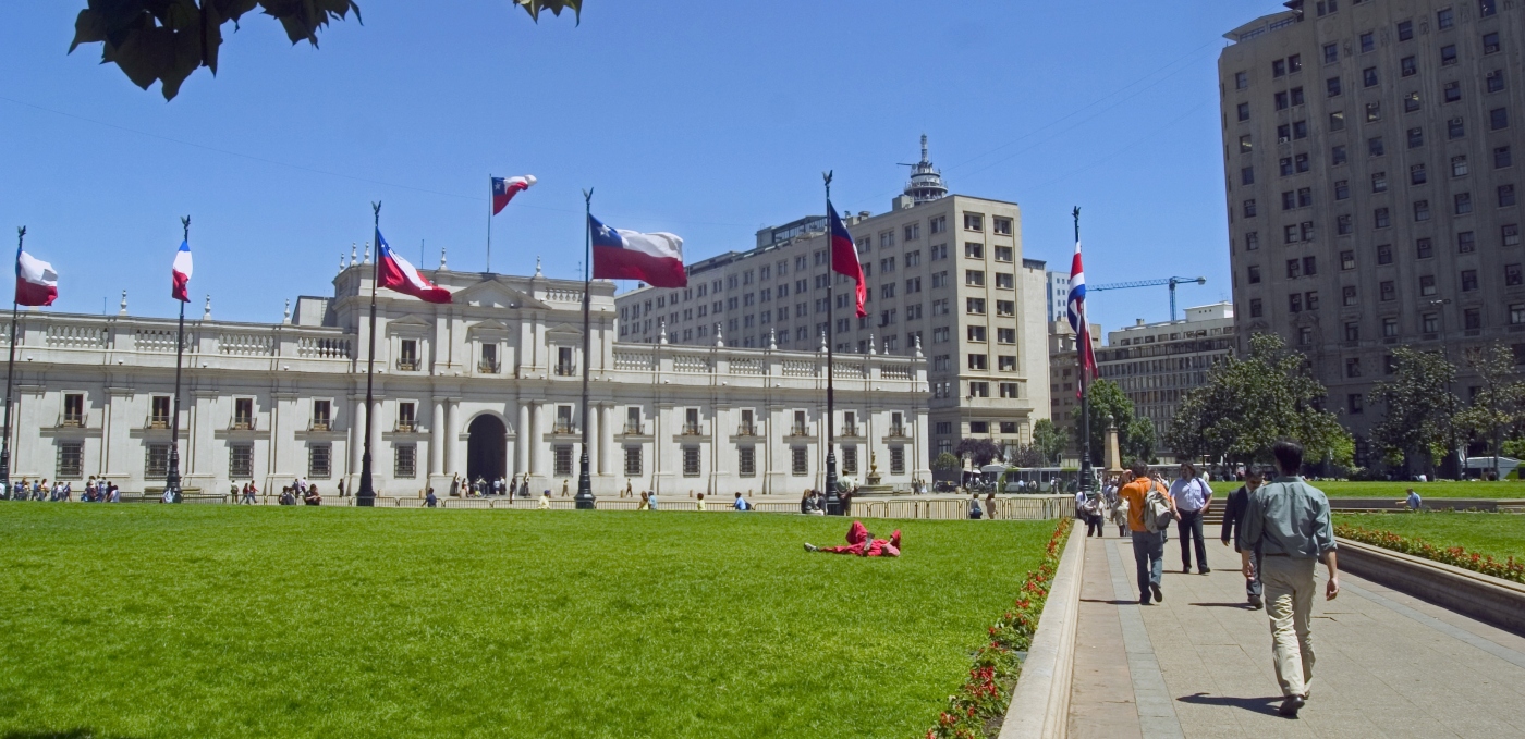 imagen panorámica del Palacio de La Moneda rodeado de banderas chilenas flameando