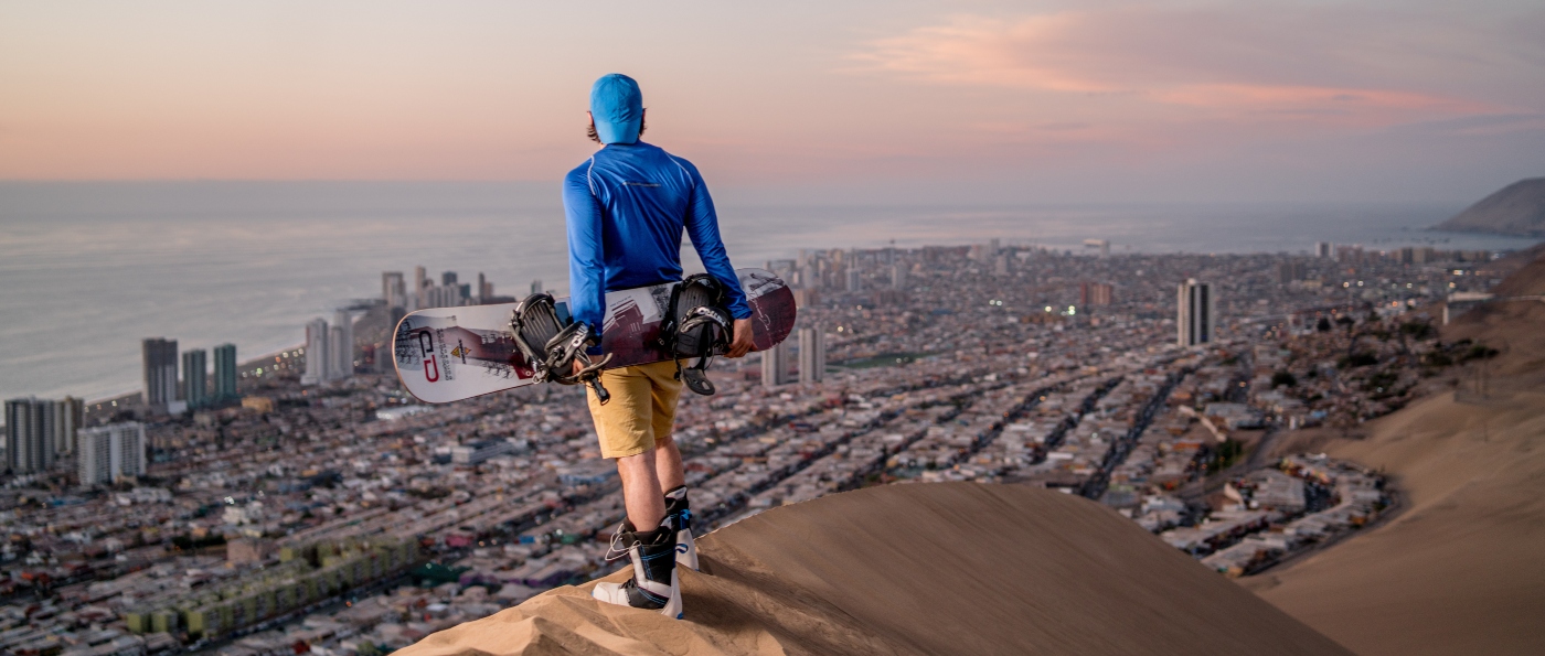 Imagen d euna joven admirando la vista desde la cima de una duna de arena en el norte de Chile