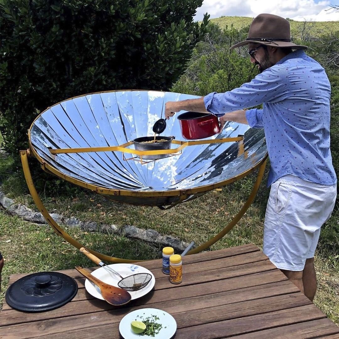 Homem cozinhando em fogão solar