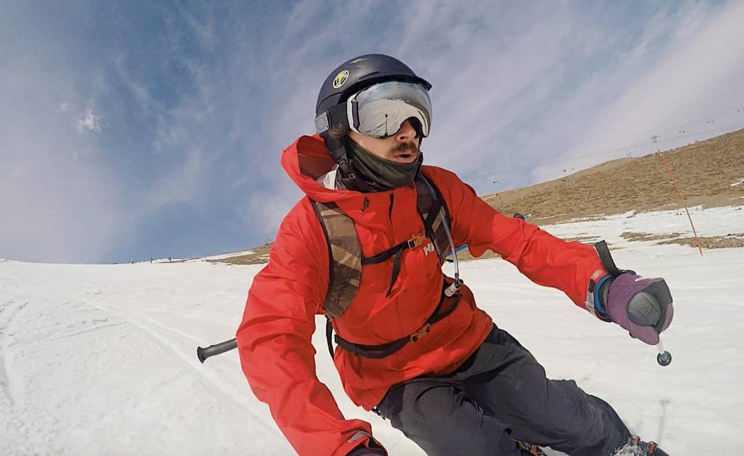 Hombre con todos sus implementos esquiando montaña abajo