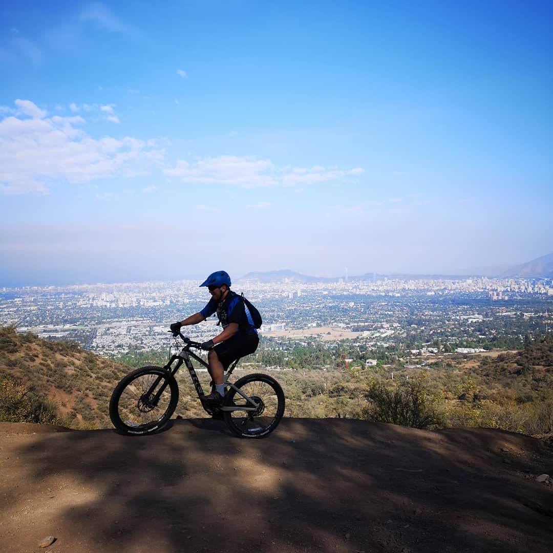 Mountainbiker auf dem Gipfel des Mahuida Parks mit der Stadt Santiago im Hintergrund