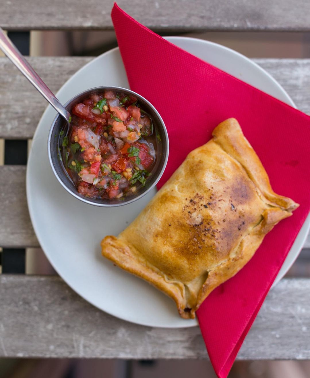 Chilean empanada on a dish with a side of pebre