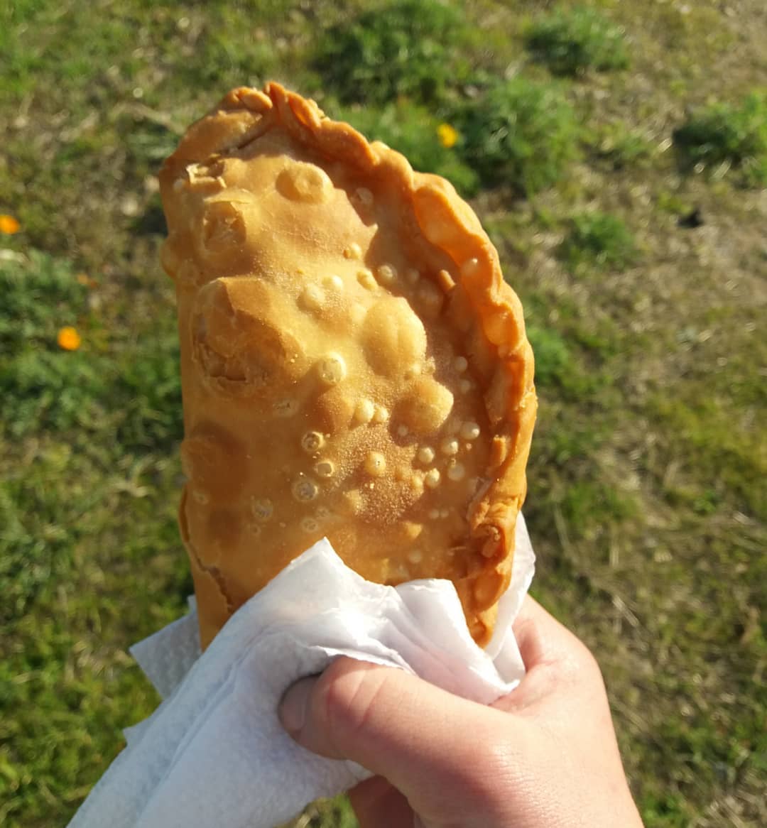 Mano sosteniendo una empanada frita