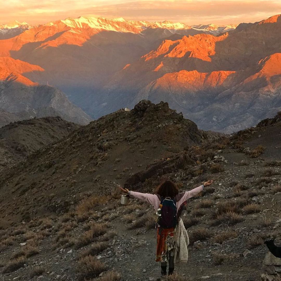 Woman opening arms to receive energy from the mountains of Los Andes, Chile