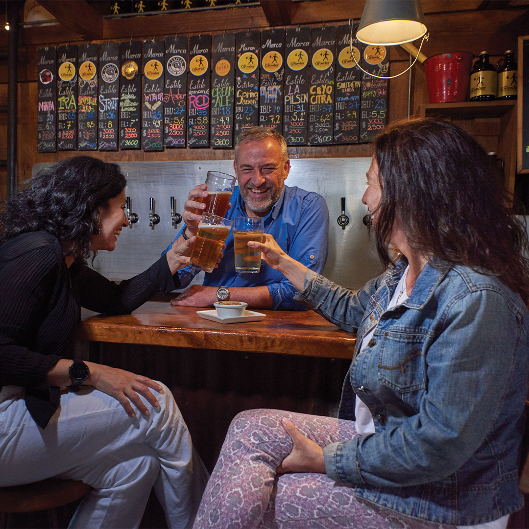 Três amigos rindo enquanto bebem cerveja artesanal, Valdivia, sul do Chile